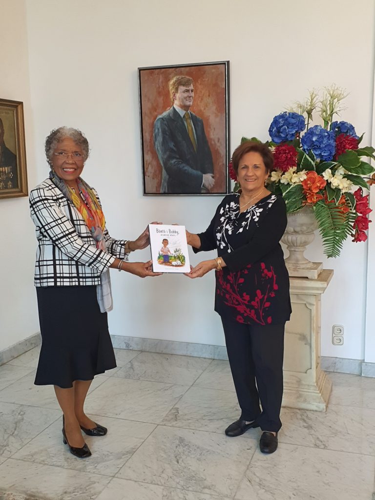 Ditiana Hollander-Elhage offers her book to the Governor of Curaçao