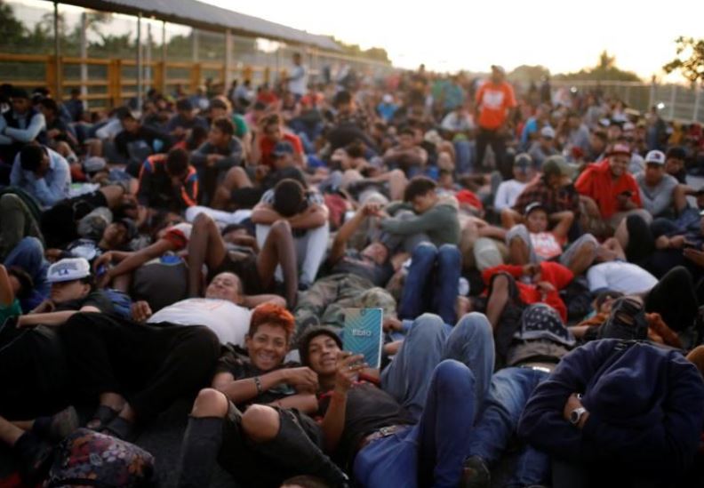 Central American migrants ford river into Mexico, chuck rocks